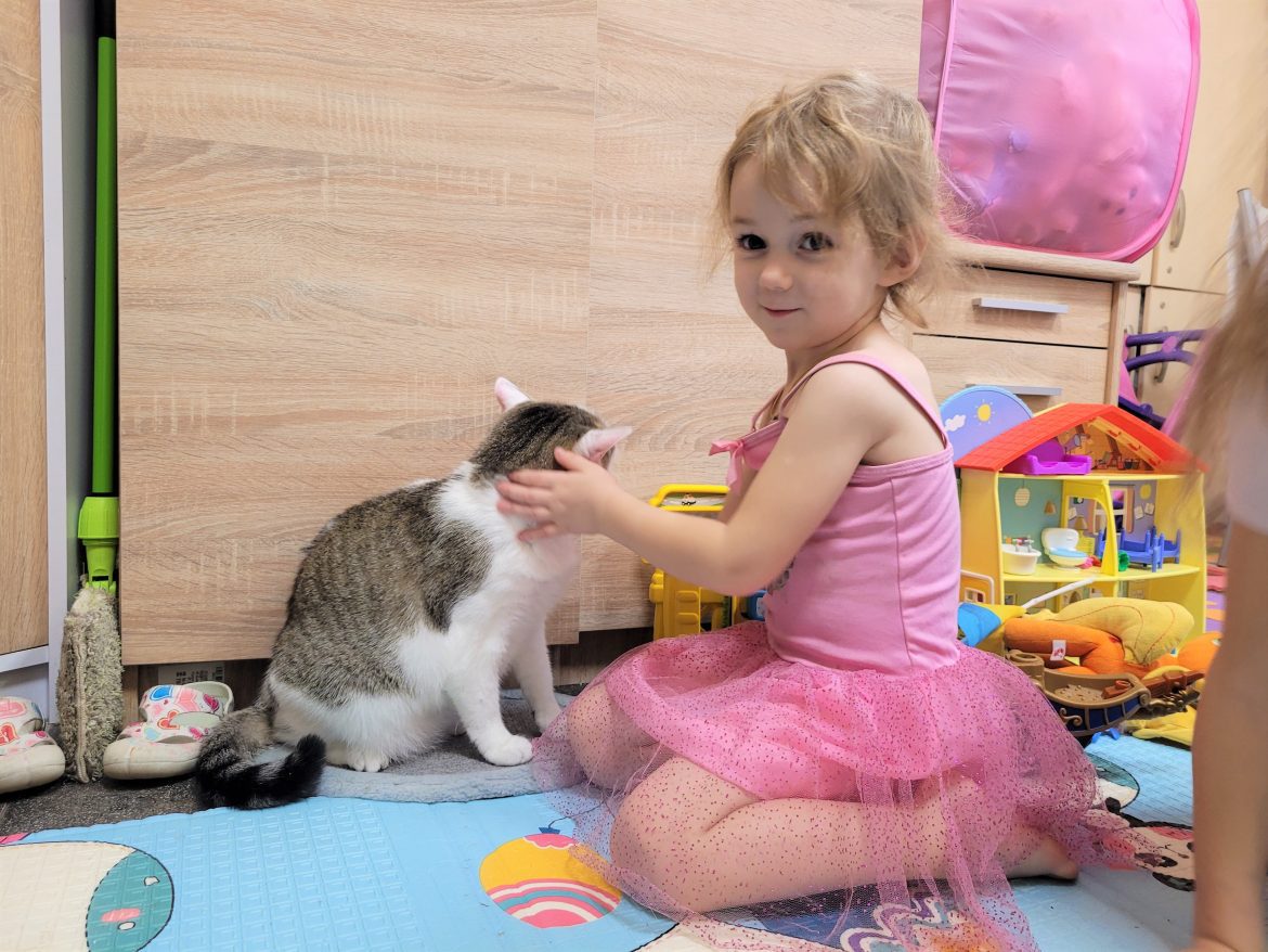 Masha mit einer Katze in einer Notunterkunft in Lwiw, Ukraine, Mädchen